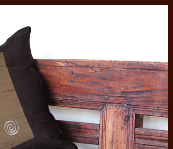 ブラウンを基調としたクッションカバーは表面の異なる２色のブラウンの渦巻きの刺繍が特徴的。